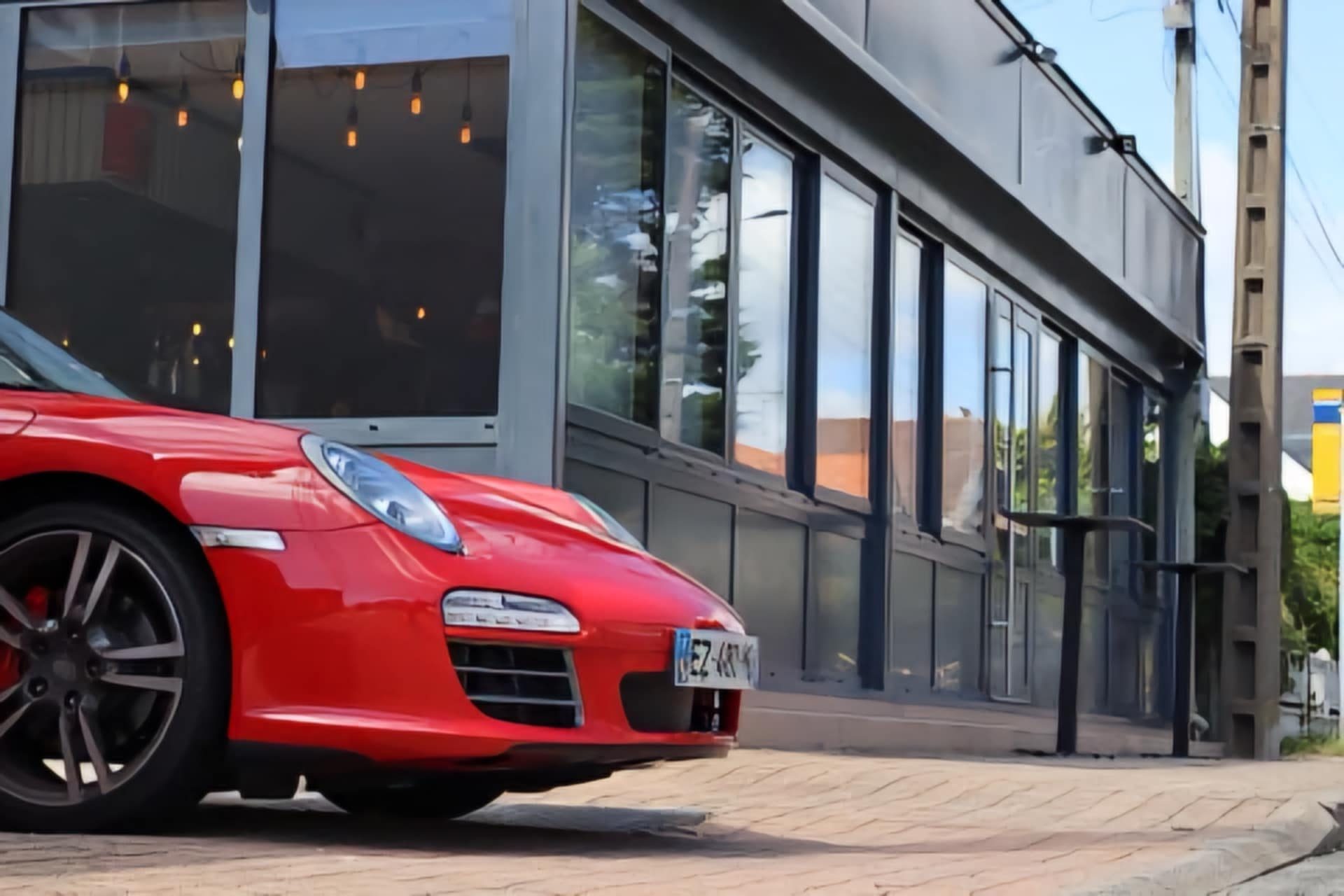 Une Porsche 911 rouge garée devant la façade du restaurant Le P911 à Pornichet